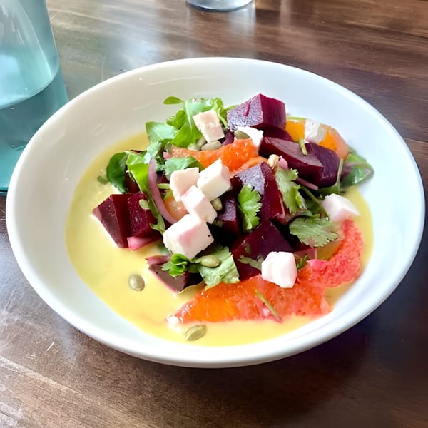El Cedro's vibrant beet and citrus salad with feta, greens, and pumpkin seeds in a yellow dressing.