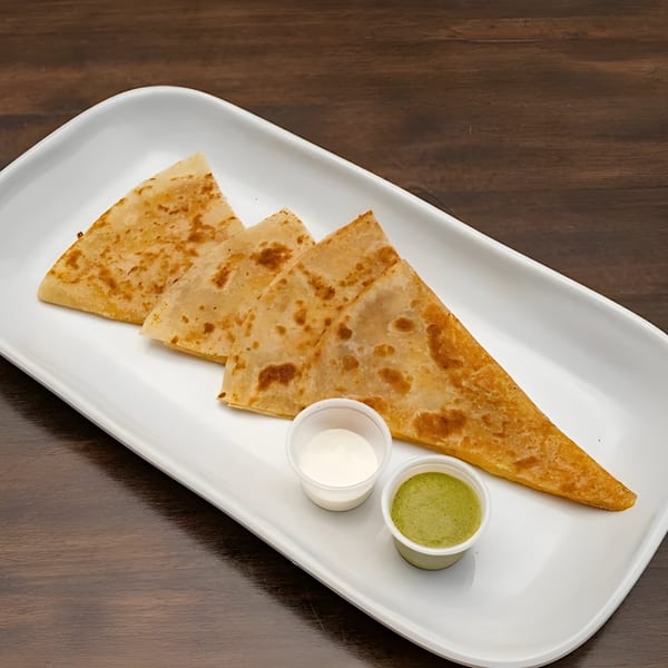 Three triangular Lebanese flatbread pieces with white and green dipping sauces on a white plate.